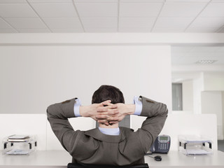 Rear view of a male office worker relaxing at desk