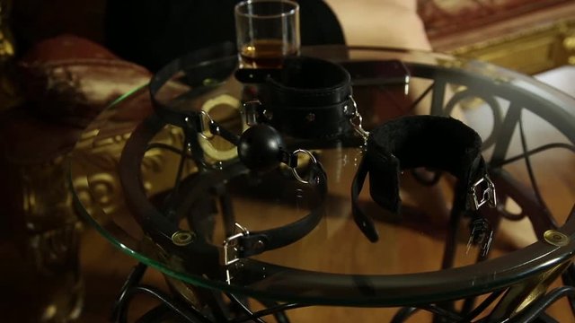 young woman takes glasses and calling on a phone. closeup BDSM accessories and sex toys.