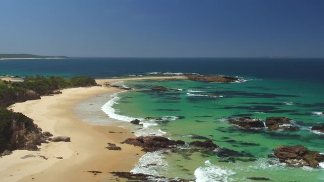 AERIAL: Flying above pretty diversified ocean bay, green sea and sandy beach 