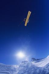 Fototapeta na wymiar Low angle view of skier jumping from mountain cliff against blue sky