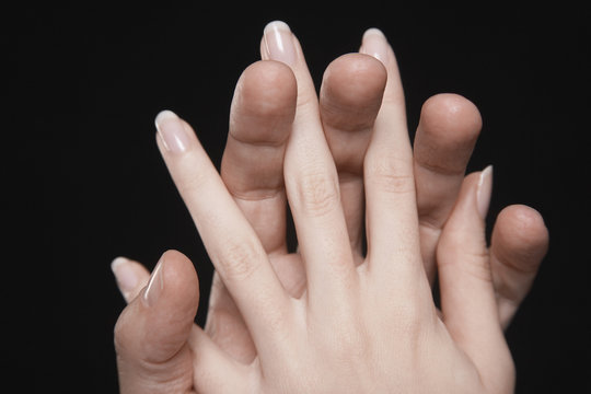 Closeup Of Couple Hands With Fingers Interlocked Together Against Black Background