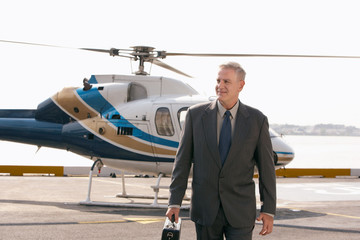 Smart middle aged businessman arriving on helicopter pad