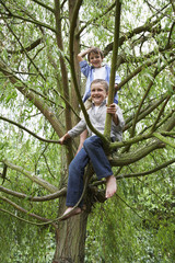 Naklejka na ściany i meble Full length of boys playing on tree branch in park