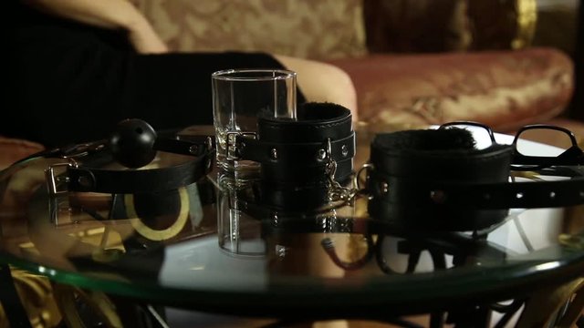 young woman takes glasses and handcuffs. closeup BDSM accessories and sex toys.