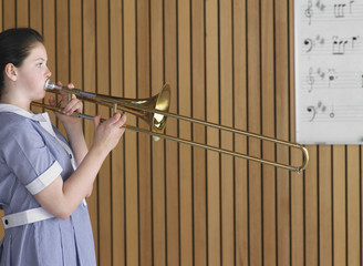 Side view of high school girl playing trombone in music class