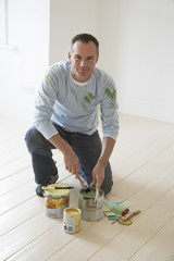 Portrait of a man kneeling on floor with painting materials