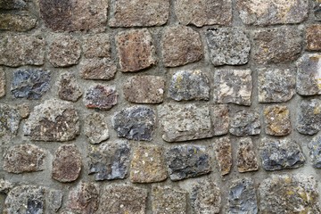 Texture of gray stone wall covered with lichen