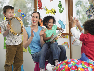Young teacher with children playing music in classroom