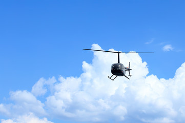 Front view of a black helicopter on blue sky