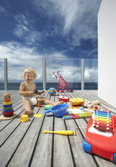 Full length of happy baby boy playing with lots of toys on wooden porch