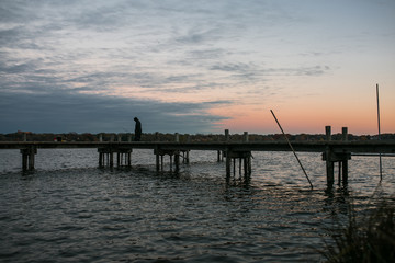 Fototapeta na wymiar Fisher Man on a Bridge During Sunset At White Rock Lake, Dallas