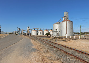 Obraz premium railway tracks and wheat silos against a bright blue sky