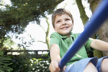 Young boy sitting on monkey bars in the backyard