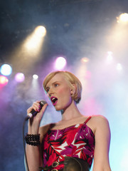 Low angle view of a beautiful young woman singing in concert on stage