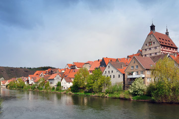 Fototapeta na wymiar Riverside with historical landmarks, towers, half-timbered houses and trees on the background the stormy sky. Besigheim, Baden-Wurttemberg, Germany.