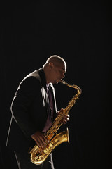 Fototapeta na wymiar Side view of an African American man playing saxophone against white background
