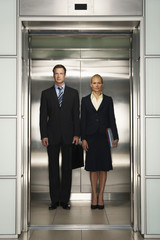 Front view of confident businessman and businesswoman standing together in elevator