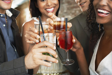 Closeup of happy multiethnic couples toasting drinks at the bar