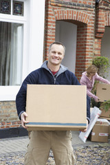 Portrait of a happy man carrying box with woman in the background