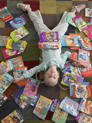 Fototapeta na wymiar High angle view of girl lying on library floor with books scattered around