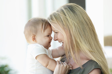 Closeup side view of a happy young mother and baby smiling into each other's eyes