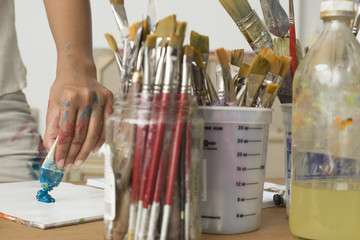 Closeup midsection of an artist squeezing paint on palette