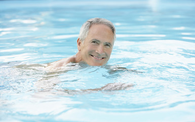 Portrait of happy middle aged man swimming in pool