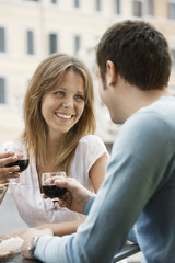 Happy young couple toasting wine glasses at outdoor cafe in Rome