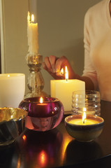 Closeup midsection of a woman lighting candles on table
