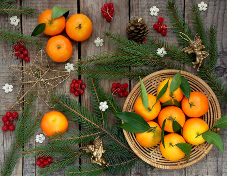 Basket of ripe mandarins, spruce branches and christmas toy on a wooden background. selective focus.