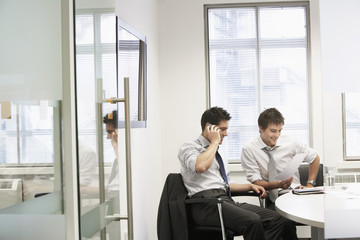 View through doorway to casual meeting between two relaxed young businessmen