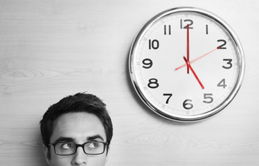 Headshot young businessman looking at clock on wall in office