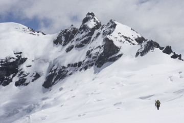 Rear view of a hiker heading towards the distant peak in snow