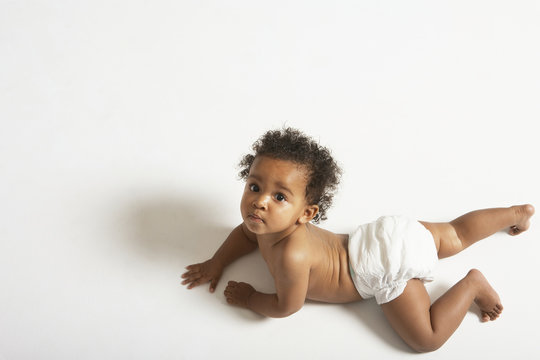 High angle portrait of cute baby crawling on white background