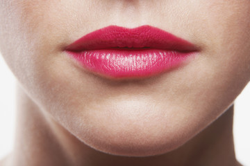 Fototapeta premium Closeup of woman wearing pink lipstick on white background