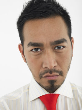 Closeup portrait of a young man frowning against white background