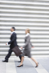 Side view of blurred businessman and woman walking quickly
