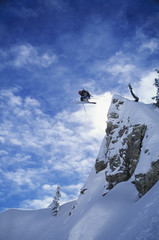 Skier jumping from mountain ledge against clear sky