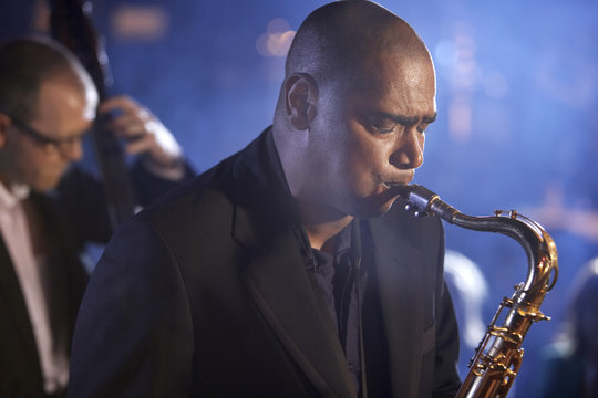 Saxophone player with man playing double bas in background on stage
