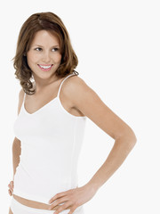 Young smiling woman in camisole with hands on hip against white background