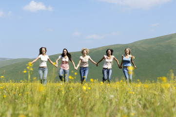 Group of happy multiethnic female friends running against mountain range