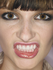 Fototapeta premium Extreme closeup of a beautiful angry young woman clenching teeth