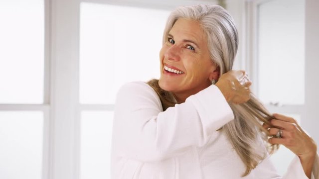 Portrait of senior caucasian woman combing healthy hair