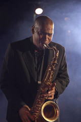 Jazz musician playing saxophone on smokey stage
