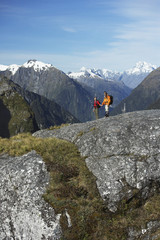 Fototapeta premium Male and female hikers on rock against mountains