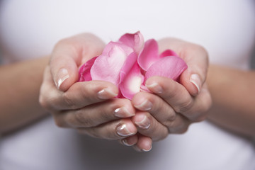 Closeup midsection of a woman holding hands full of petals - obrazy, fototapety, plakaty