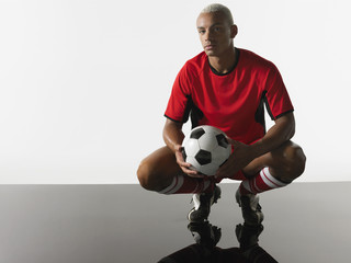 Portrait of a player squatting with football in hands against white background