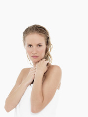 Portrait of a young blond woman wrapped in towel against white background