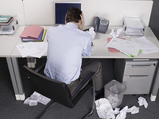 Rear view of a businessman with head in hands at office desk