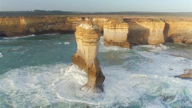 AERIAL: Flying around high limestone formation rising from shallow water 